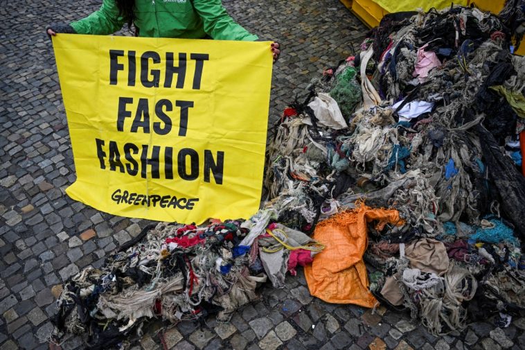 Ativistas do Greenpeace protestam no Portão de Brandemburgo contra a poluição do meio ambiente em Gana causada por roupas de fast fashion como resíduos plásticos.